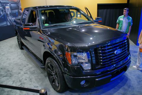 1993 Ford Taurus - A black Ford F-150 truck is displayed at an auto show with its driver's door open.
