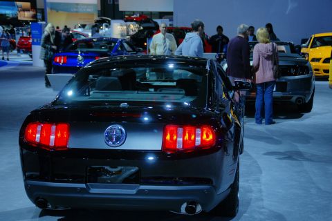 1993 Ford Taurus - Rear view of a black Ford Mustang at an auto show, with other vehicles and attendees present.