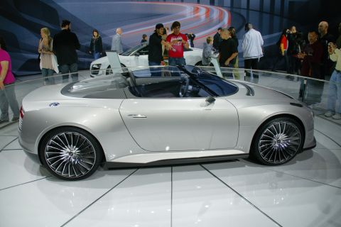 1993 Ford Taurus - A silver concept convertible is showcased at an auto show with a crowd observing.
