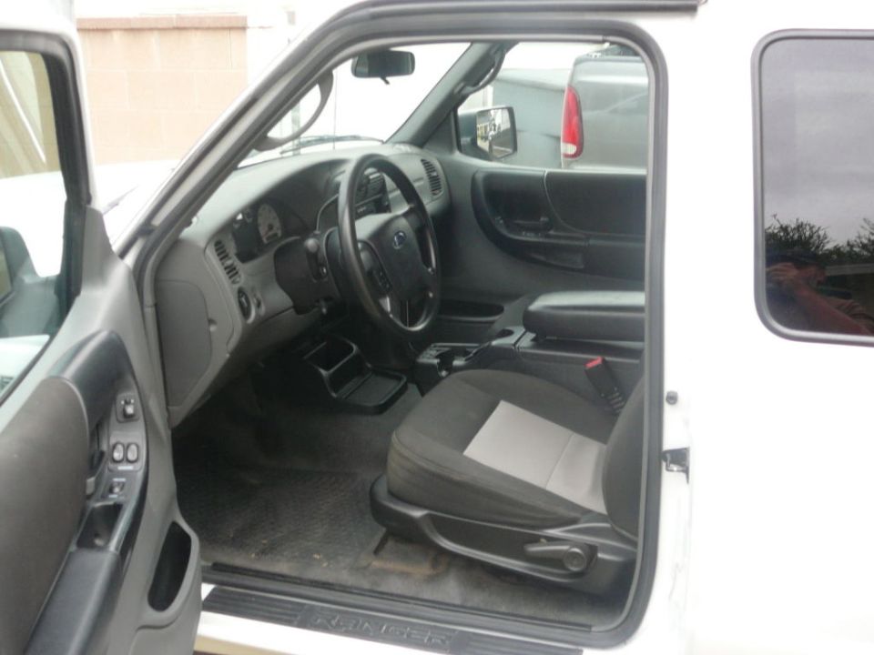 Interior of a white Ford Ranger pickup truck, showing the driver's seat, dashboard, and steering wheel