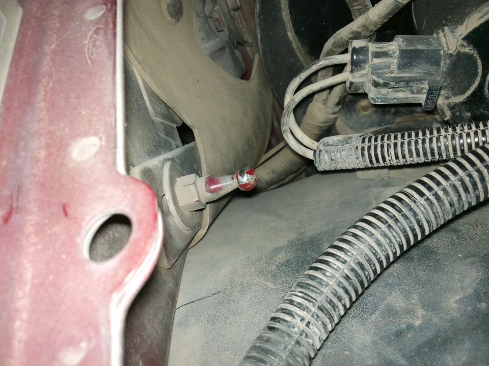 Close-up of a red and silver hood latch mechanism with wires and corrugated tubing