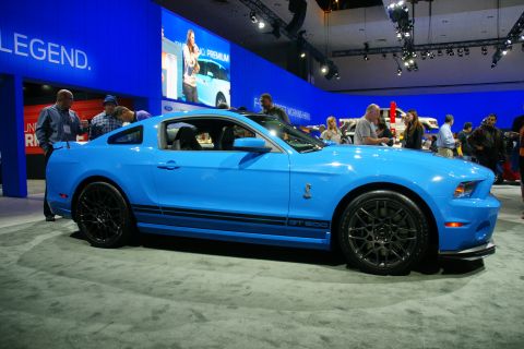 1993 Ford Taurus - A bright blue Ford Mustang Shelby GT500 is showcased at an auto show with people looking on.