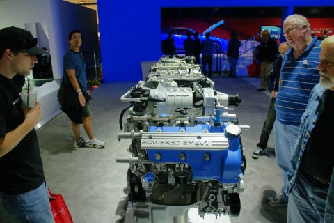 1993 Ford Taurus - An SVT engine is displayed at an auto show, with onlookers gathered around.
