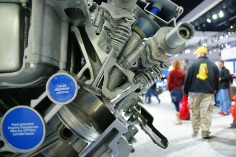 1993 Ford Taurus - A cutaway engine display shows internal components and features, with attendees in the background at an auto show.