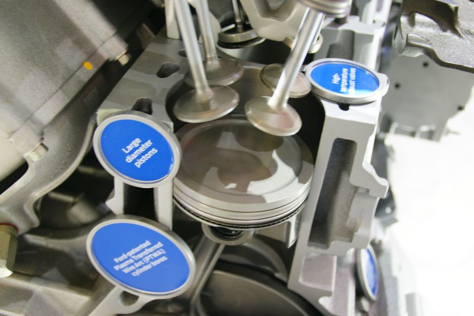 Engine cutaway showing pistons, valves, and cylinder bores with informational labels