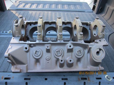 1969 Ford Mustang - A bare engine block rests in the bed of a truck, showing its internal structure and bearing cap mounts.