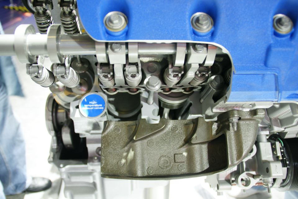 Cutaway view of an engine with a blue valve cover, showing internal components and a label for high-temperature exhaust valves