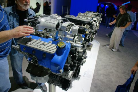 1993 Ford Taurus - A V8 engine is on display at an auto show, with onlookers examining it.