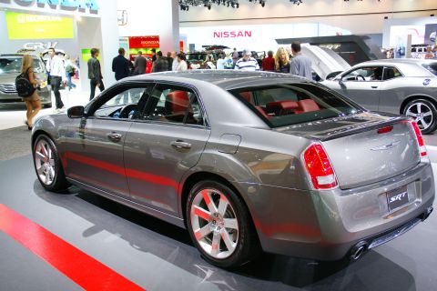 1993 Ford Taurus - A gray Chrysler 300 SRT sedan is displayed at an auto show with other vehicles in the background.