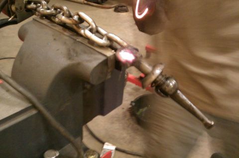 1987 Ford Bronco - A chain is secured in a vise while a metal rod is heated to a glowing red color.