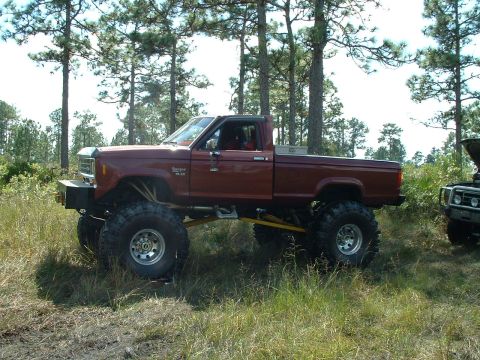 1995 Ford Bronco - This lifted Ford Ranger pickup truck is modified for off-road use and is parked next to another vehicle.