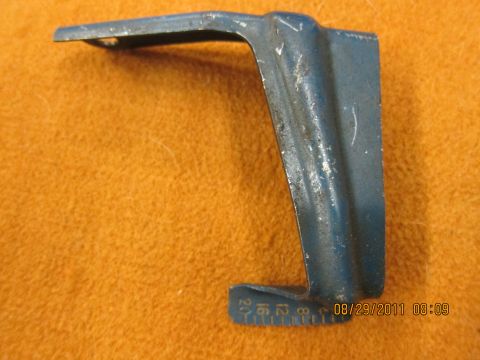 1969 Ford Mustang - A blue metal bracket with etched measurement markings is shown against an orange textured background.