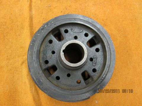 1969 Ford Mustang - A close-up view of a car part, a crankshaft pulley, is shown against a textured orange background.