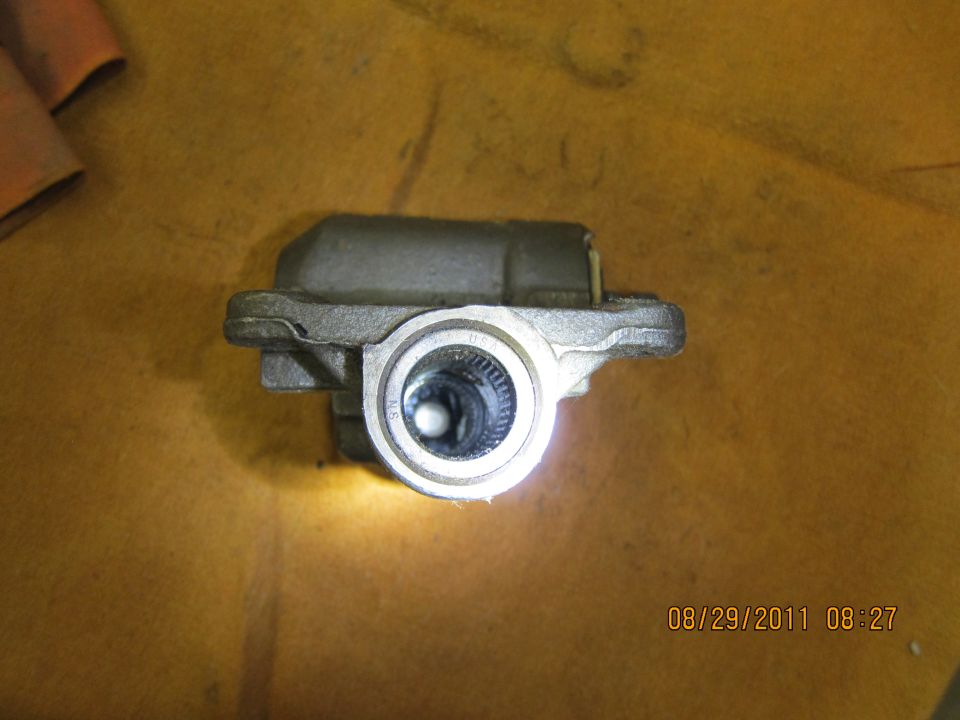 Automotive part with a circular opening showing internal splines, on a yellow surface
