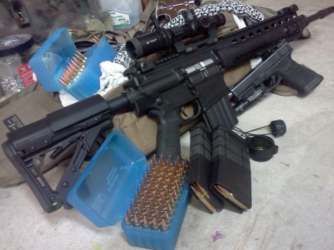 1996 Ford Bronco - An assault rifle with a scope, a pistol, and multiple magazines and boxes of ammunition are laid out.