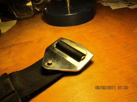 1969 Ford Mustang - A close-up view of a seatbelt buckle and strap, with a timestamp and website visible in the lower right corner.