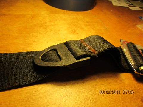 1969 Ford Mustang - Close-up of a black seat belt buckle and strap with visible stitching and a metal clasp.