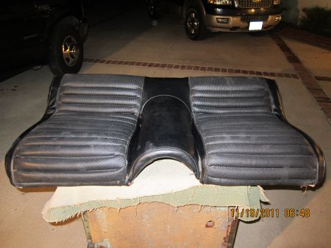 1969 Ford Mustang - A black car seat with a distinctive ribbed pattern is shown, with two SUVs in the background.