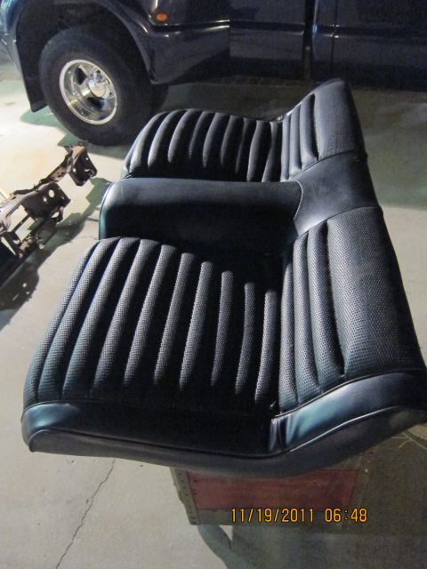 1969 Ford Mustang - Black vinyl bucket seats with ribbed pattern are shown next to a dark-colored truck.