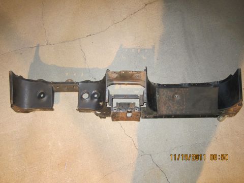 1969 Ford Mustang - A disassembled dashboard frame lies on a concrete surface, showing its internal structure and mounting points.