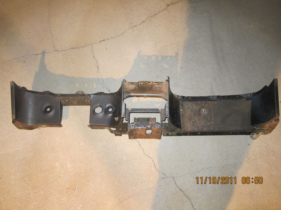 Black metal dashboard frame with circular cutouts and mounting brackets, resting on concrete