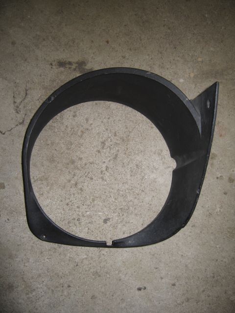 1969 Ford Mustang - A black plastic headlight bezel, likely for a classic car, is shown against a concrete background.