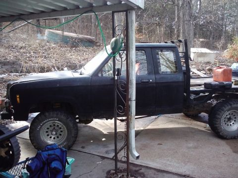 1988 Ford Ranger - Side view of a black 1988 Ford Ranger extended cab pickup with a flatbed and lifted suspension.