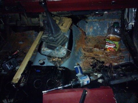 1988 Ford Ranger - The interior of a truck shows significant rust and damage, with a floor shifter and tools present.