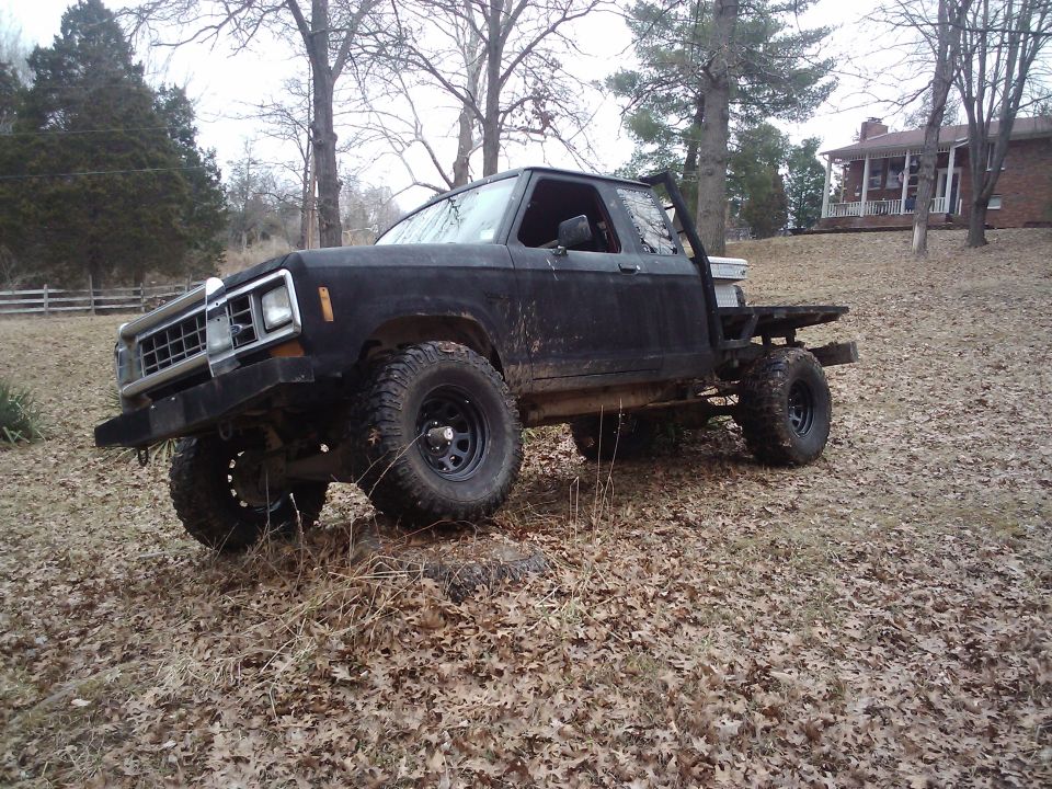 1988 Ford Ranger pickup with flatbed, lifted, off-road tires, parked in a yard