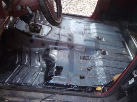 1988 Ford Ranger - The bare interior floor pan of a vehicle, showing the transmission tunnel and a portion of the steering wheel.