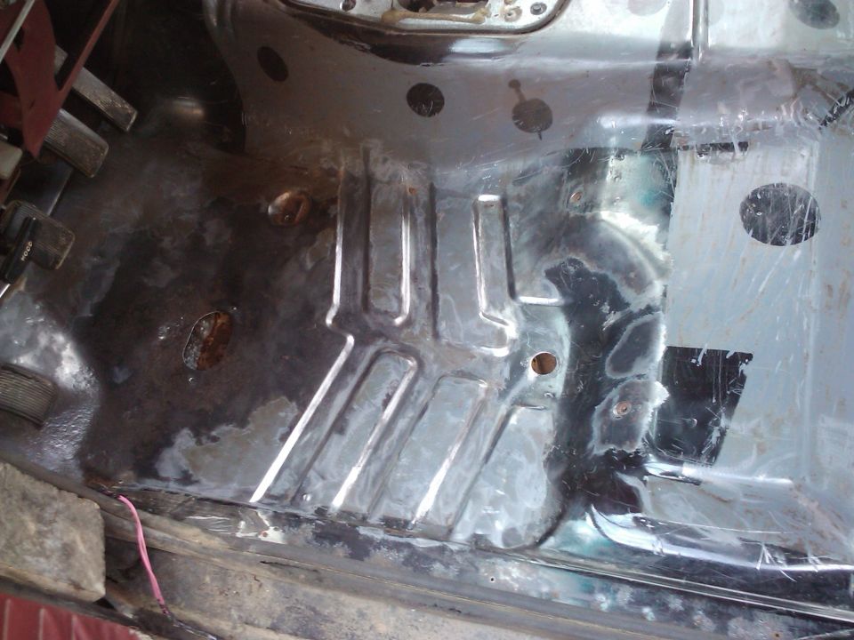 Interior floor pan of a vehicle, showing metal bracing and some rust damage