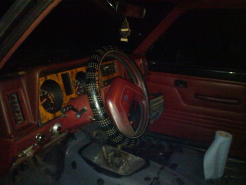 1988 Ford Ranger - The interior of a vehicle shows a dashboard with wood-grain accents and red door panels.