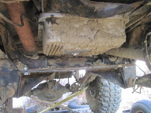 1978 Ford Bronco - Mud-caked drivetrain parts are visible on the underside of a vehicle.