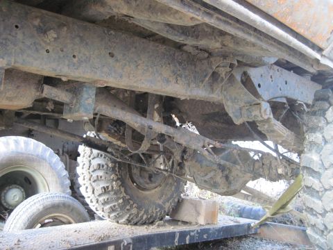 1978 Ford Bronco - The underside of a heavily soiled vehicle reveals its suspension components and large tires.