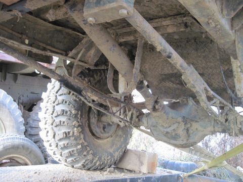 1978 Ford Bronco - Mud-covered undercarriage and rear axle of a truck, with large tires visible.