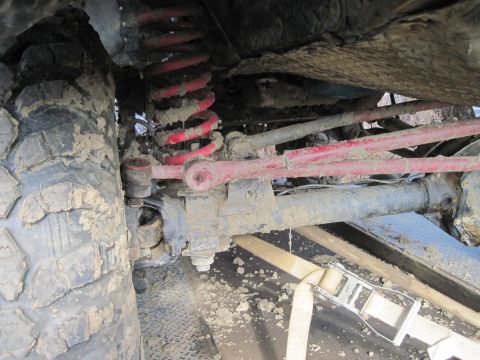 1978 Ford Bronco - Close-up view of the muddy suspension and tire of an off-road vehicle.