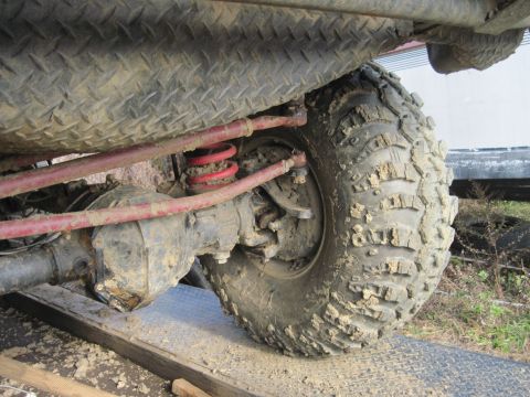 1978 Ford Bronco - Close-up view of the rear axle, suspension, and a large, mud-caked off-road tire.