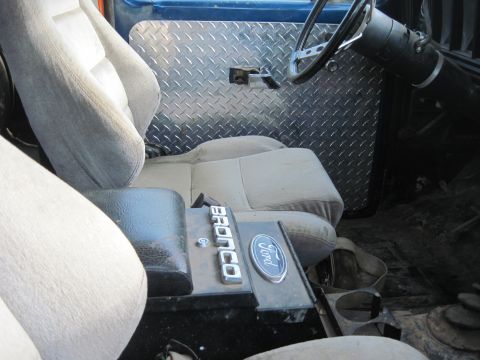 1978 Ford Bronco - The interior of a Ford Bronco shows cloth seats and a diamond plate door panel.