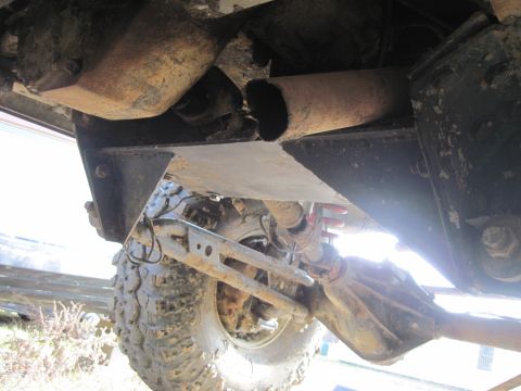 1978 Ford Bronco - The undercarriage of the vehicle reveals its suspension components and a section of the exhaust pipe.