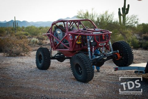 Suzuki Samurai - Custom tube-frame buggy with large tires is being loaded onto a trailer in a desert environment.