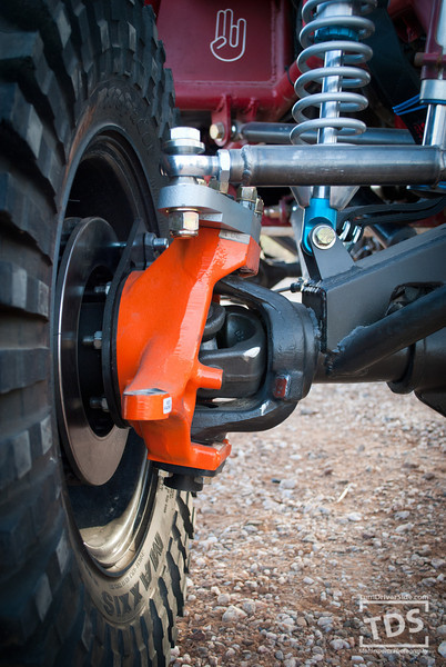 Suzuki Samurai - Close-up of an off-road vehicle's suspension system, showing the tire, brake rotor, and suspension components.