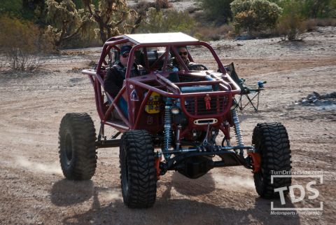 Suzuki Samurai - Custom off-road buggy with two occupants driving on a dirt track.