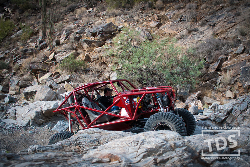 Red off-road buggy navigating rocky terrain