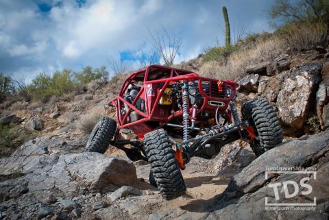 Suzuki Samurai - This heavily modified buggy navigates a challenging rocky trail under a cloudy sky.