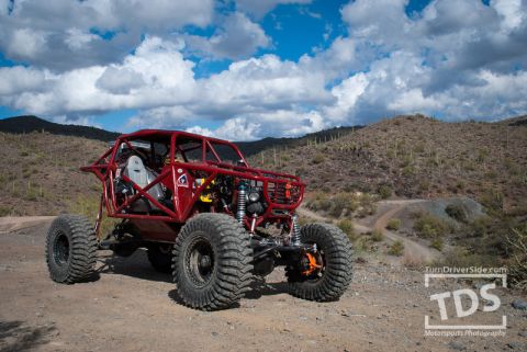 Suzuki Samurai - A custom-built off-road buggy sits on a dusty trail with desert hills in the background.
