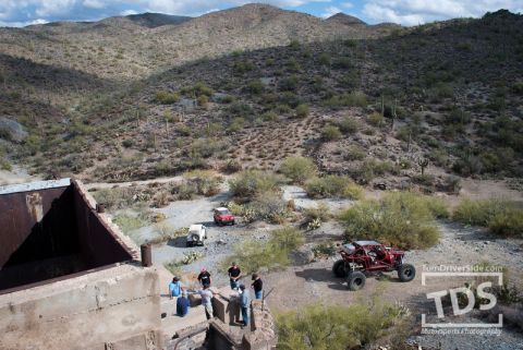 Suzuki Samurai - Off-road vehicles explore a desert terrain, with a red buggy and two SUVs visible near a ruined structure.
