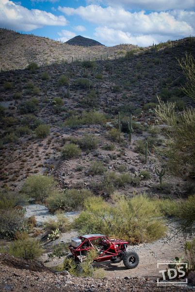 Suzuki Samurai - Red off-road buggy navigates a desert trail under a cloudy sky.