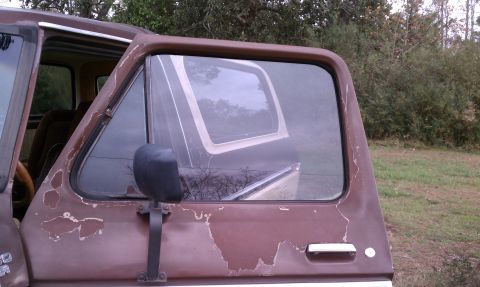 1979 Ford Bronco - A weathered 1978 Ford Bronco sits outdoors with its driver's side door ajar.