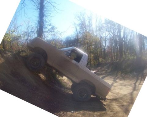 1989 Ford Bronco - A lifted pickup truck navigates a challenging off-road trail during daylight hours of-road event.