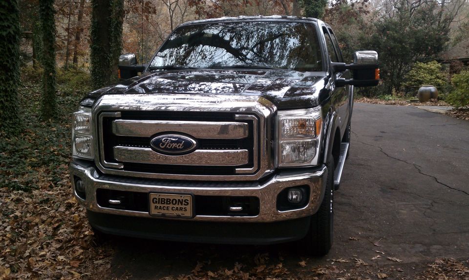 Front view of a black Ford F-Series truck with a chrome grille and a 'GIBBONS RACE CARS' license plate